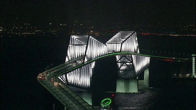 当一架飞机在羽田机场附近的跑道上移动时，闪烁的灯光标记着东京门大桥的塔。视频下载