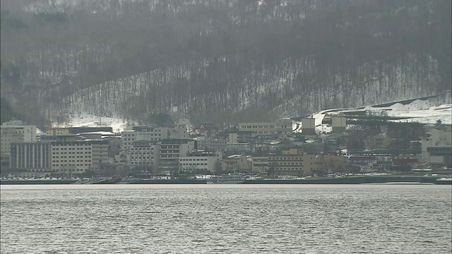 白雪覆盖的乌苏山耸立在洞谷湖和北海道的温泉小镇上。视频素材