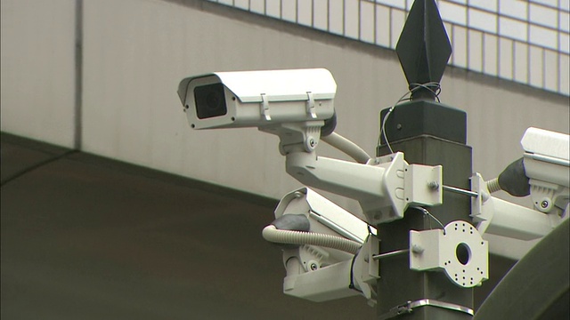 监控摄像头被安装在城市街道上方的路灯上。视频素材