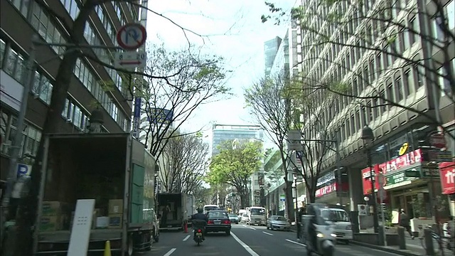 在东京道根坂街上，一名摩托车手跟在一辆货车后面。视频素材