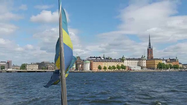 瑞典斯德哥尔摩，一艘挂着瑞典国旗的船在夕阳中缓缓移动视频素材