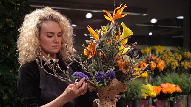 花店里的卖花女孩拿着一束漂亮的花束视频下载