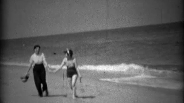 1936年:姐妹们穿着泳装和高腰裤在沙滩上散步。视频素材