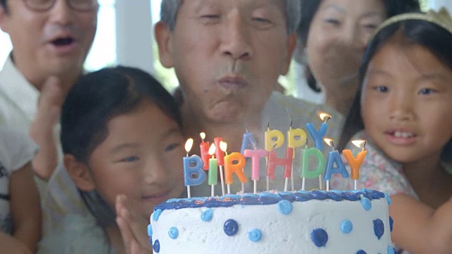 爷爷吹灭生日蛋糕上的蜡烛视频素材