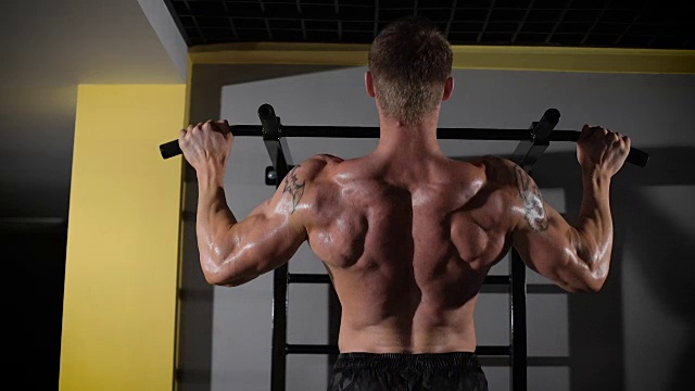 一个肌肉发达的人在健身房的工作室收紧的背影肖像视频下载