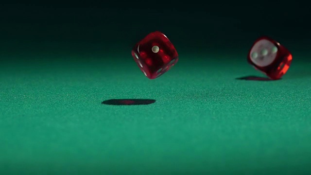 慢镜头里，红色的骰子落在绿色的赌桌上。视频素材