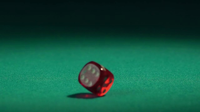 红色的骰子在慢镜头落在绿色的桌子上。赌场视频素材