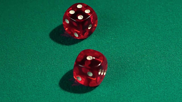 宏观上看红色的骰子落在绿色的桌上，玩视频素材