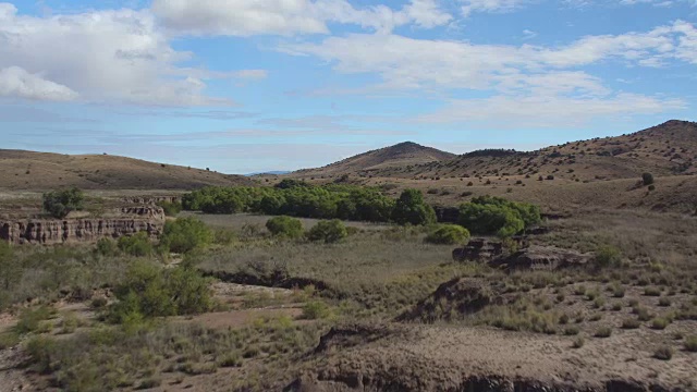 AERIAL:令人惊叹的美丽的干燥河床峡谷和茂密的沙漠山丘视频素材