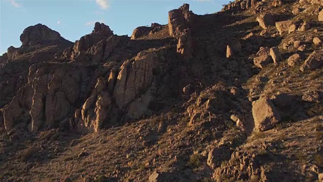 航拍:在日落时分飞过岩石沙漠的山顶视频素材