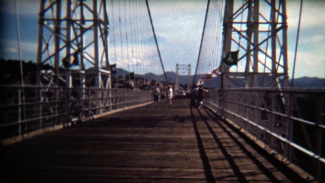 1972年:人们在刮风的日子走过桥，旗帜飘扬。视频下载