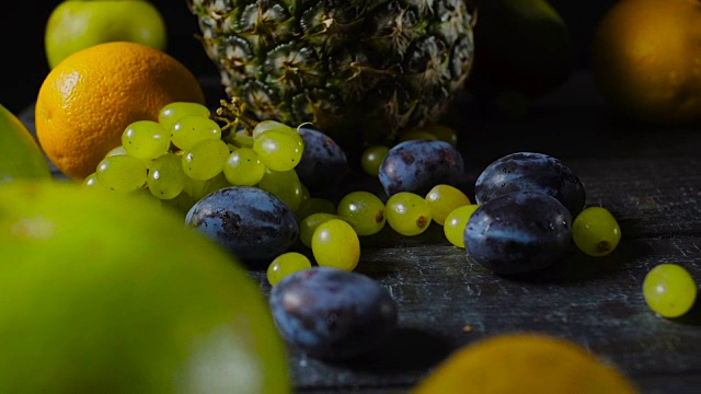 木桌上的李子、葡萄和热带水果视频素材