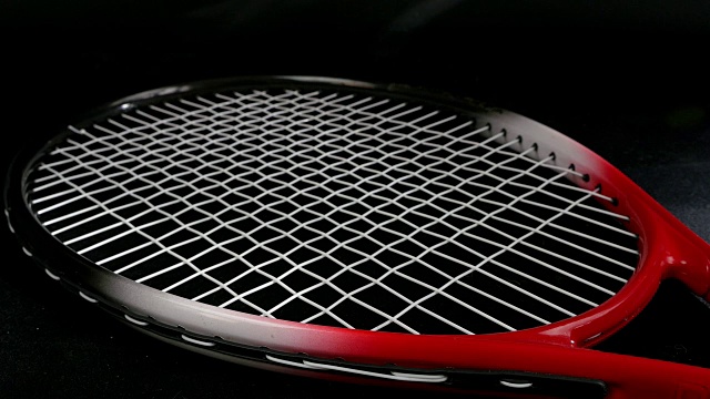 手把两个网球放在网球拍上，以黑色为背景视频下载