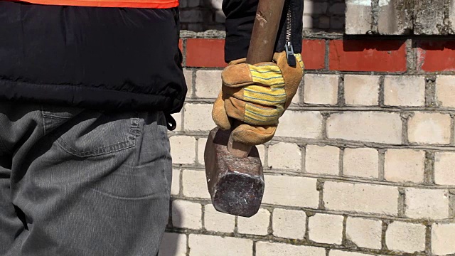工人拿着大锤靠近砖墙视频素材