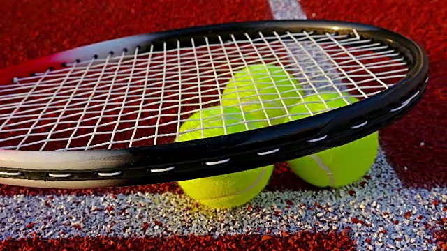 网球拍和球躺在红色的网球场上视频下载