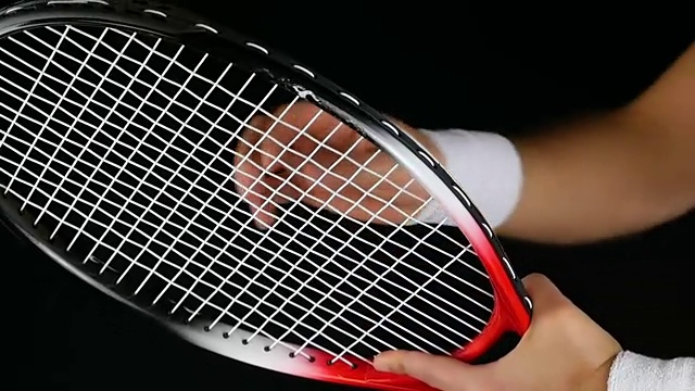 一个网球运动员的手调整网球拍网的慢动作，黑色背景视频下载