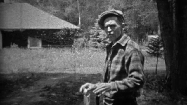 1935年:一个男人骄傲地举着刚捕到的鳟鱼，抽烟斗。视频素材