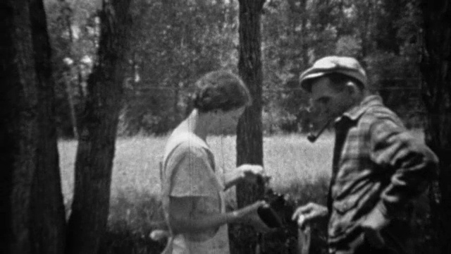 1935年:一名男子向一名女子拍照，她举着最近捕获的鳟鱼。视频素材