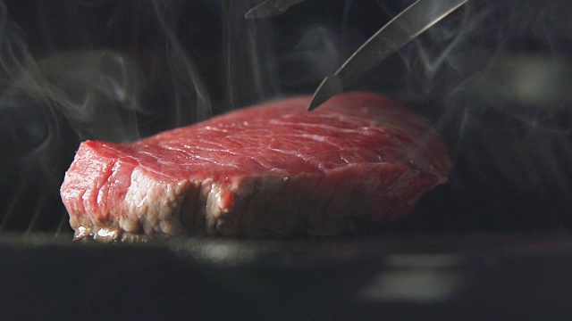 慢炖:厨师在烤架上翻转一块牛排视频下载