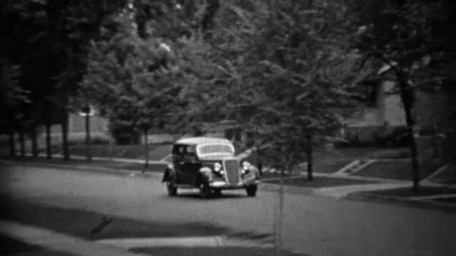 1935年:经典新款黑色普利茅斯轿车开在居民区。视频素材