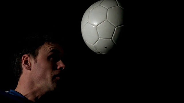 足球运动员头球在黑色背景视频素材