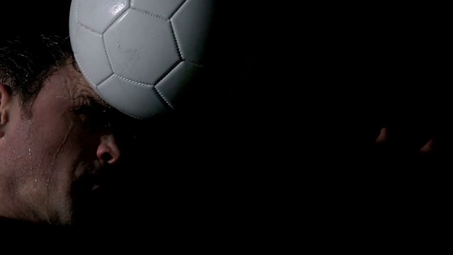 足球运动员头球在黑色背景视频素材