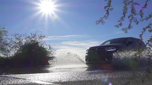 慢镜头:一辆SUV从大水坑上冲过，把水溅到摄像机上视频素材