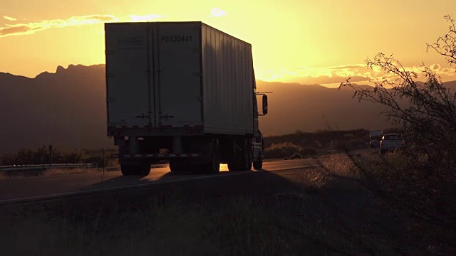 在金色的夏日夕阳下，汽车和货运卡车在高速公路上行驶视频素材
