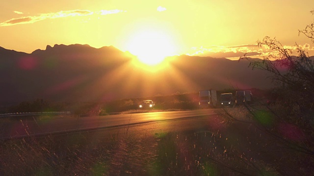 在金色的夕阳下，汽车和货运卡车在繁忙的公路上行驶视频素材