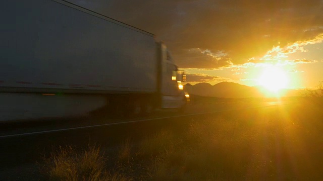 一辆货车在空旷的高速公路上飞驰，在夏日日落的金色阳光下视频素材
