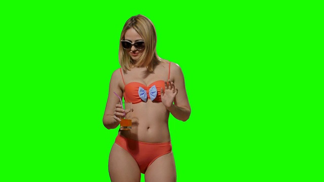 金发女郎在海滩上穿着泳衣喝着果汁(阿尔法频道)视频素材