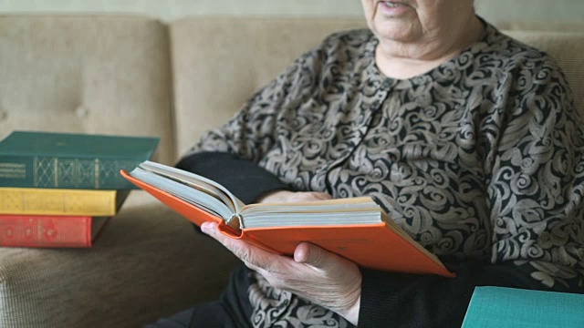老妇人坐在椅子上读一本厚厚的书视频素材