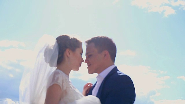 一对美丽的恋爱中的年轻夫妇刚刚在阳光下结婚接吻视频素材
