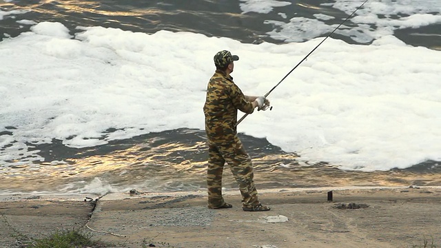 一个年轻人在湖边钓鱼视频素材
