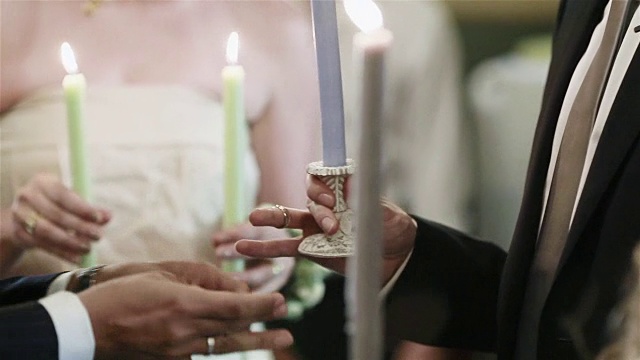 希腊和保加利亚东正教的仪式、传统和习俗。伴郎Koumbaro把戒指戴在新郎和新娘的半指上——在新婚夫妇之间交换结婚戒指。近距离视频素材
