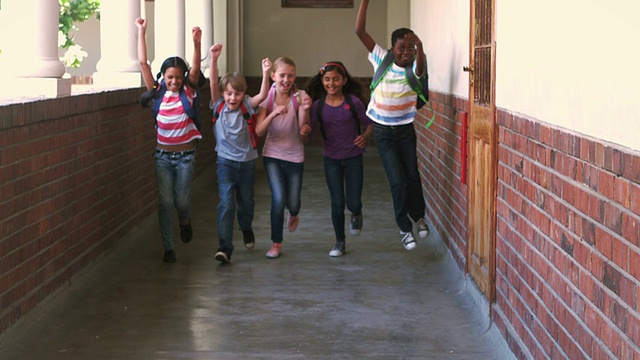 在走廊里，可爱的学生们对着镜头奔跑微笑视频下载