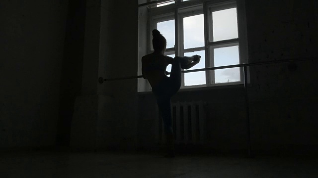一个芭蕾舞演员在窗边的栏杆上锻炼的剪影视频下载