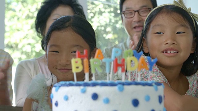 女孩吹灭生日蛋糕上的蜡烛时的慢动作镜头视频素材
