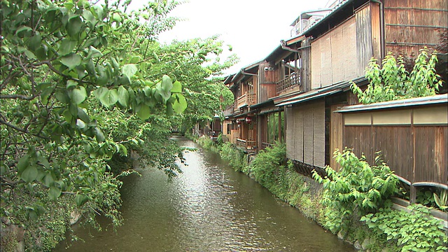 一条河流过河岸上的木制建筑。视频素材