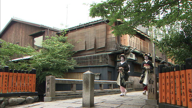 京都东山区，一名舞妓和一名艺妓走过一座木桥。视频素材