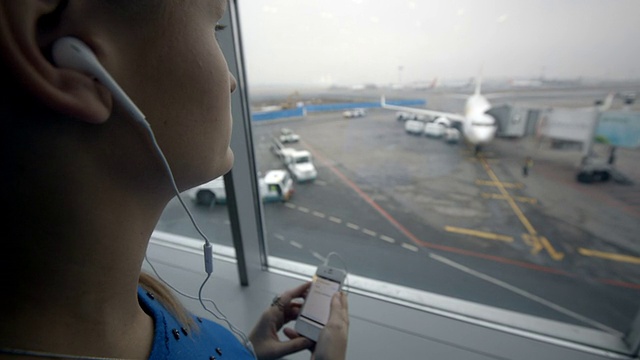 在机场靠窗听音乐的女人视频素材