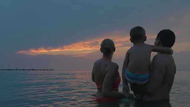 父母和儿子一边洗澡一边欣赏傍晚的天空视频素材