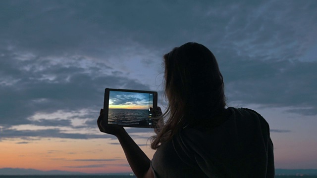 在黄昏中，用垫子拍海和天的女人视频下载