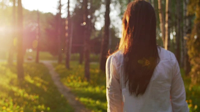 日落时分，一个女人在森林里散步。慢动作视频素材