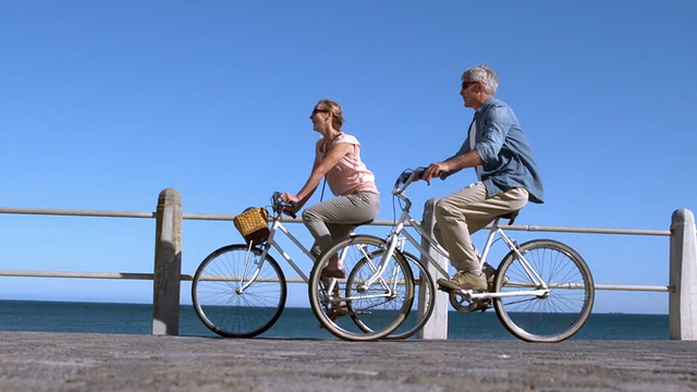 一对老夫妇在码头上骑自行车视频素材