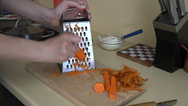 女孩在厨房用碎纸机将橙子胡萝卜磨碎视频素材