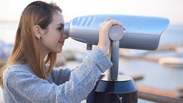 年轻女子用固定的双筒望远镜看。视频下载