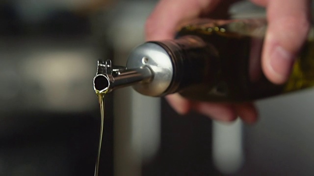 缓慢:厨师从油瓶中倒橄榄油视频素材