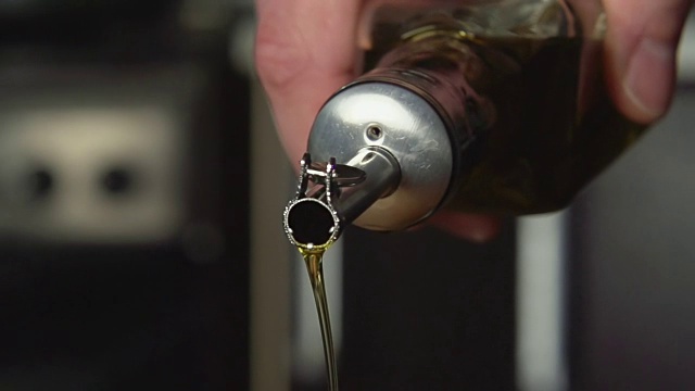 慢镜头:Сook从油瓶中倒橄榄油视频素材