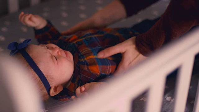 一位母亲从婴儿床上抱起啼哭的婴儿，试图让她平静下来视频素材